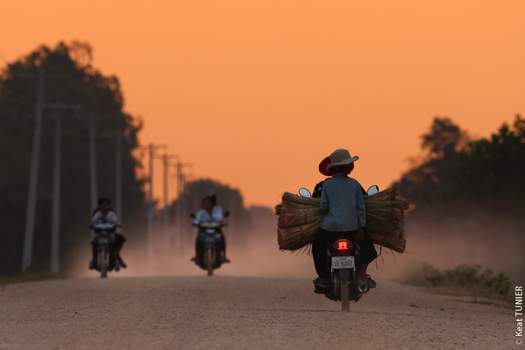 Locaux sur des mobylettes transportant des bottes de riz au Cambodge