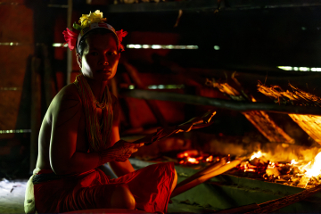 Habitante de la tribu des Mentawai devant un feu dans une maison